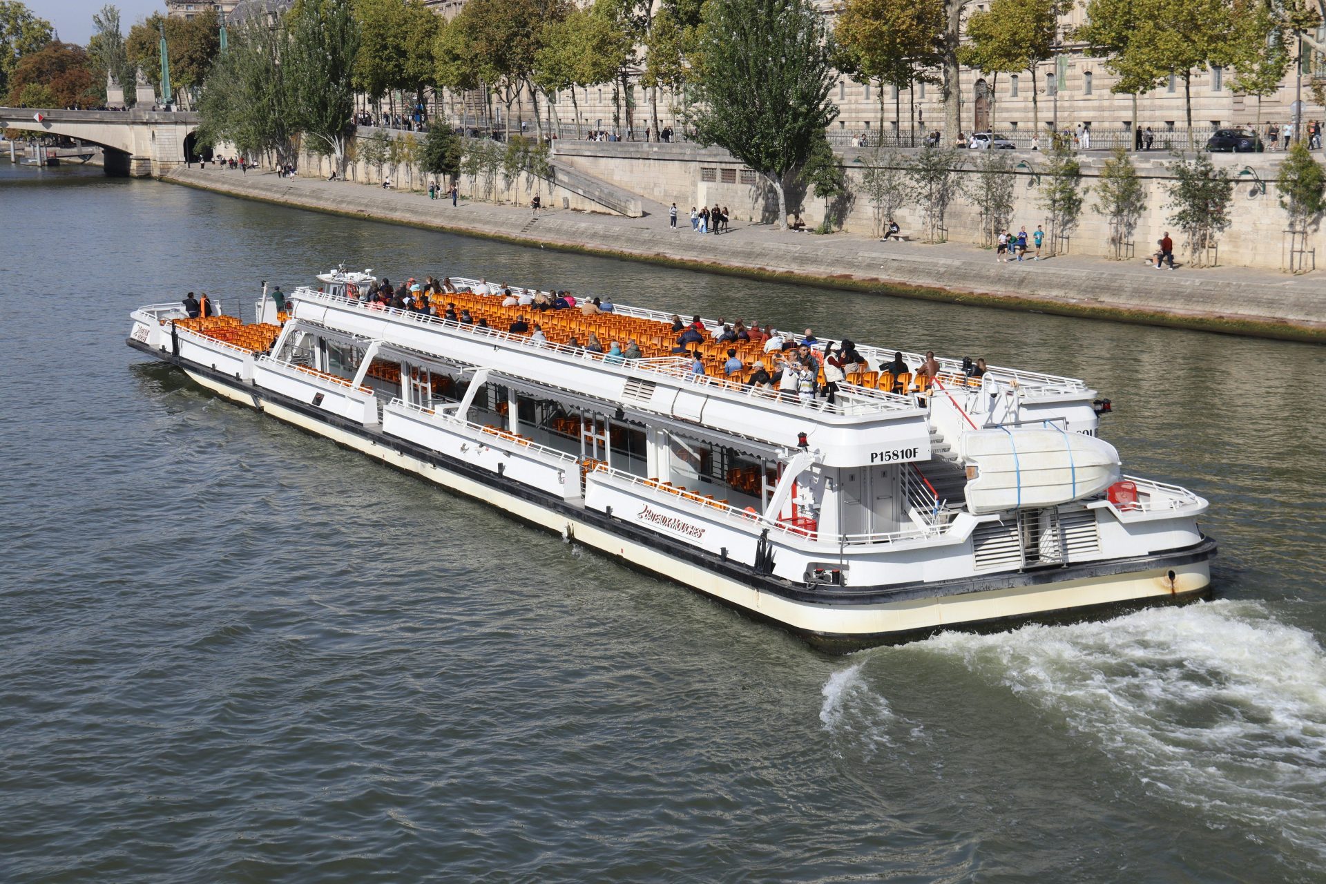 Un bateau de tourisme blanc descend une large rivière.